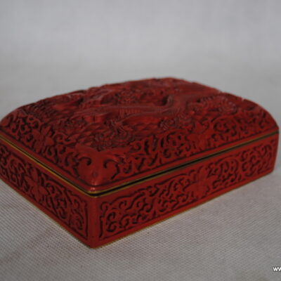 Szkatułka wyprodukowana w Chinach w II poł. XXw. Laka w czerwonym kolorze. Całość utrzymana z motywach chińskiego smoka. Wymiary: 15,5 cm x 10 cm, wysokość ok. 5,7 cm Stan bardzo dobry.